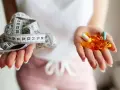 Dwie dłonie: jedna z miarką krawiecką, druga z kolorowymi kapsułkami – symbolizują wybór między dietą a środkami na odchudzanie.