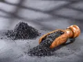 Czarna sól, czyli jodan potasu, w drewnianej łyżce i obok na kamiennym blacie.