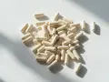 Kapsułki z probiotykami rozsypane na białym tle. Ten **symbiotyk** to wsparcie dla Twojego organizmu.