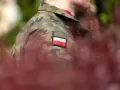 Żołnierz w mundurze z polską flagą. W tle zamazane czerwone liście i zieleń. Choroby dyskwalifikujące ze służby wojskowej mogą wpłynąć na możliwość noszenia takiego munduru.