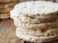 Stos wafli ryżowych na drewnianym blacie. Czy wafle ryżowe są zdrowe? To pytanie zadaje sobie wiele osób, sięgając po tę lekką przekąskę.