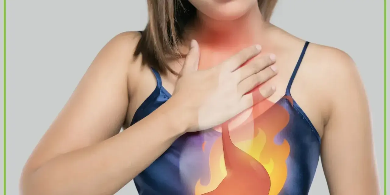 Kobieta trzyma się za klatkę piersiową, gdzie widoczny jest płonący żołądek, symbolizujący objawy refluksu.