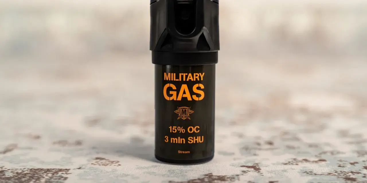 Czarny gaz pieprzowy z pomarańczowym napisem "MILITARY GAS" i informacją "Stream".