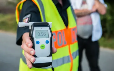 Policjant pokazuje alkomat z wynikiem 0.93 promile alkoholu. Kontrola drogowa trwa.