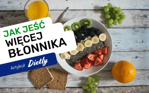 Pyszna owsianka z owocami i nasionami chia, idealna na śniadanie, które ma duzo blonnika. Obok szklanka soku i kromki chleba.