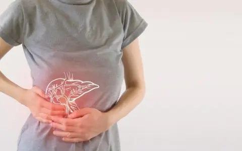 Osoba trzymająca się za brzuch, gdzie widoczny jest zarys wątroby. Może to symbolizować problemy z trawieniem lub potrzebę wsparcia enzymami trawiennymi.