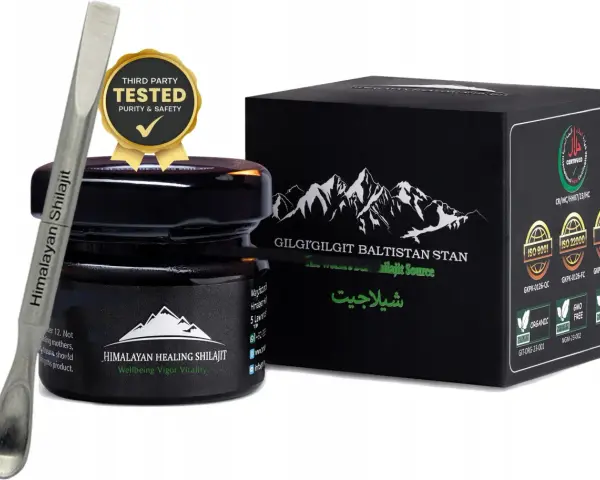 Srebrna szpatułka z napisem "Himalayan Shilajit" obok czarnego słoiczka i pudełka z górami. Certyfikaty potwierdzają jakość shilajitu.