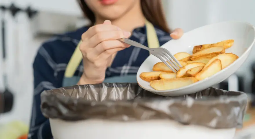 Kobieta wyrzuca frytki, zaczynając drogę do tego, jak obniżyć cholesterol bez leków. Zdrowa dieta to klucz.