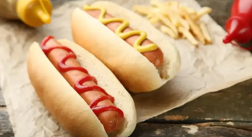 Dwa hot dogi, jeden z keczupem, drugi z musztardą, obok frytek. Zastanawiasz się, ile kalorii ma hot dog?