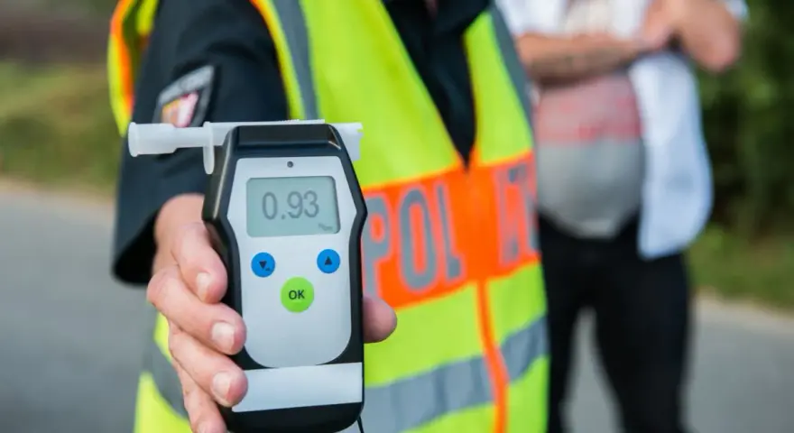 Policjant pokazuje alkomat z wynikiem 0.93 promile alkoholu. Kontrola drogowa trwa.