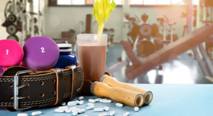 Na siłowni, obok hantli i suplementów, leżą tabletki, które mogą zawierać aminokwasy endogenne.