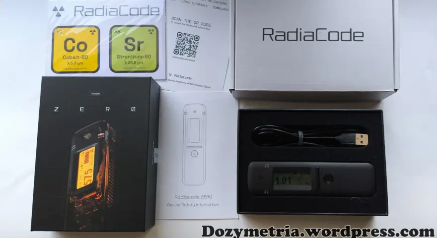 Zestaw Radiacode z dozymetrem ZERO, instrukcją i kablem USB. Obok pudełka z urządzeniem znajduje się karta z informacjami o izotopach Co-60 i Sr-90.